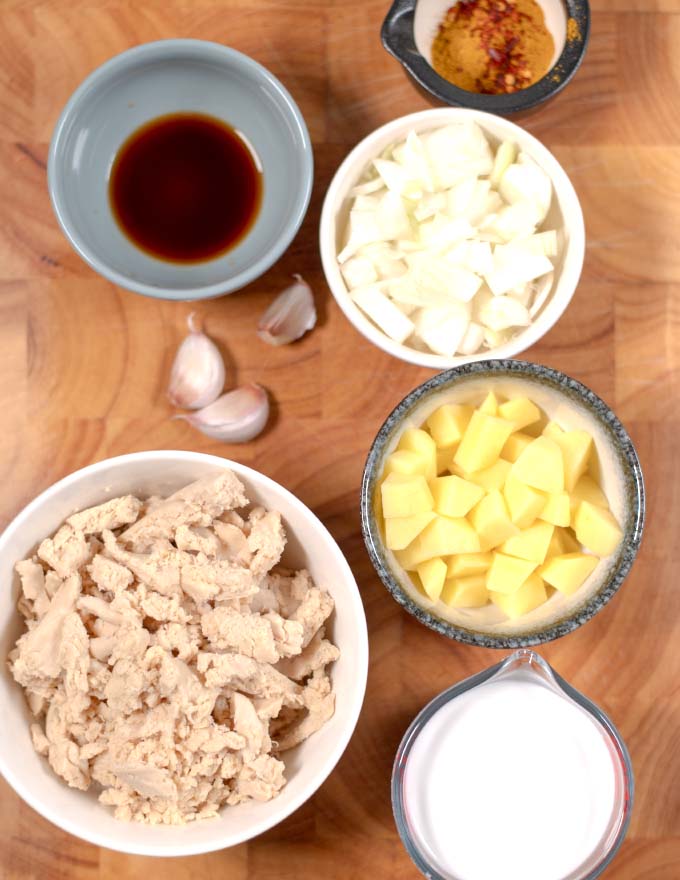 Ingredients needed to make Jamaican Curry Chicken collected on a board.