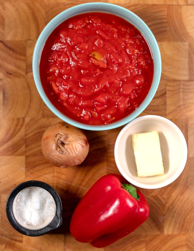 Ingredients needed to make Southern Stewed Tomatoes collected on a cutting board.