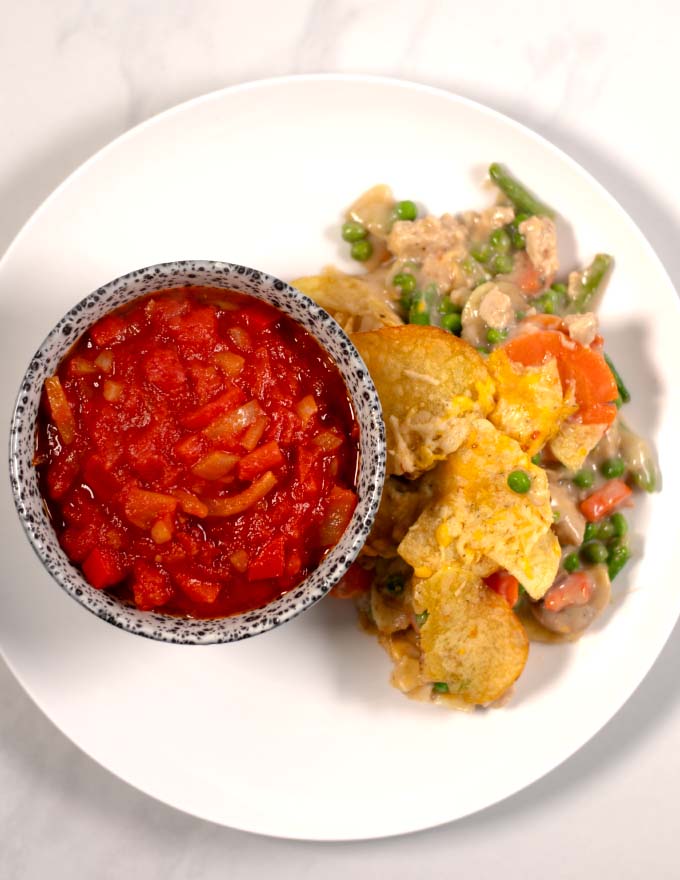 A serving of a casserole with a portion of Southern Stewed Tomatoes as side.