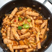 Ready Thai Chicken in a pan garnished with scallions.