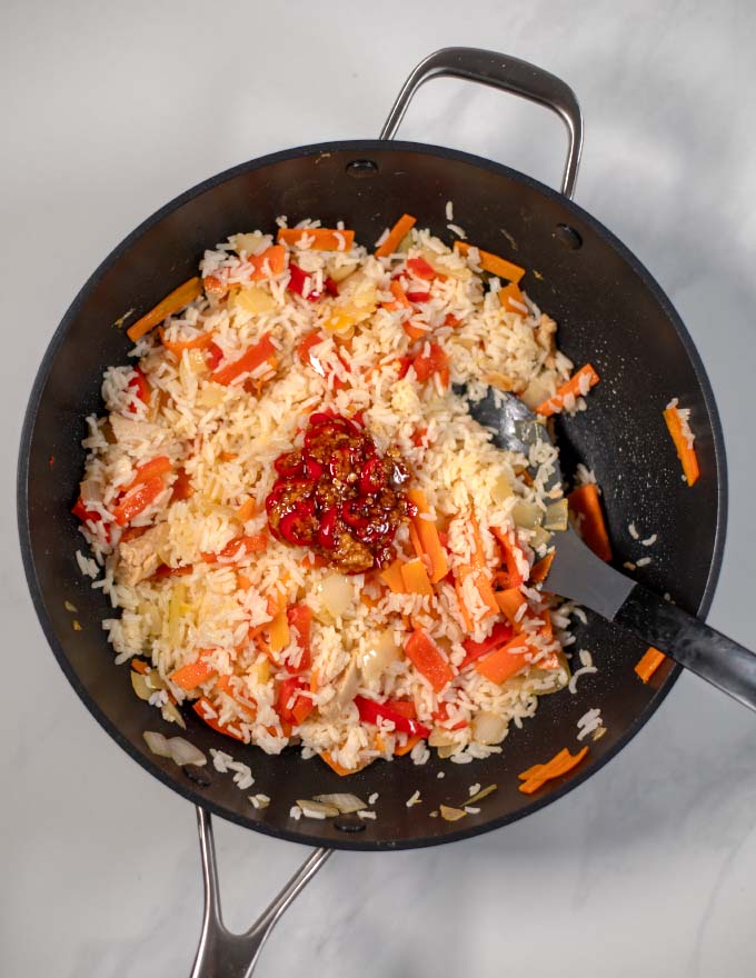 Top view of a large wok with spicy sauce added to fried rice.