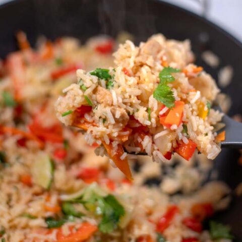 A large spoonful of Thai Fried Rice is lifted from the wok.