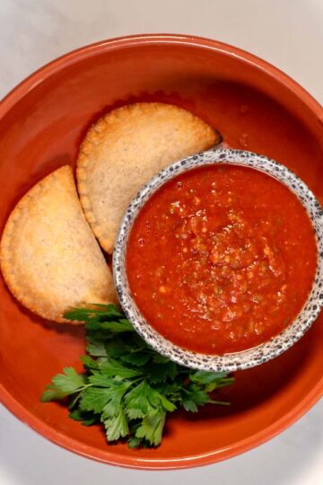 A serving of empanadas with sauce.