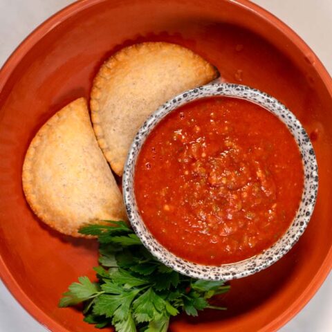 A serving of empanadas with sauce.