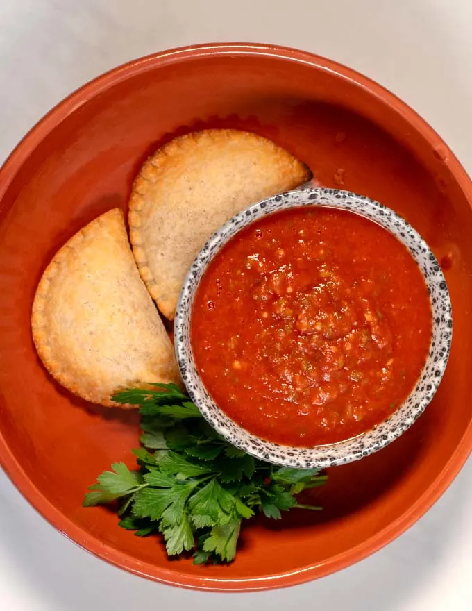 A serving of empanadas with sauce.