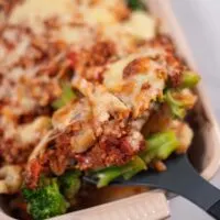 A large spoon lifts the casserole out of the baking dish.