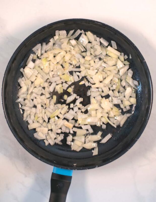 Diced onions are fried in a pan.