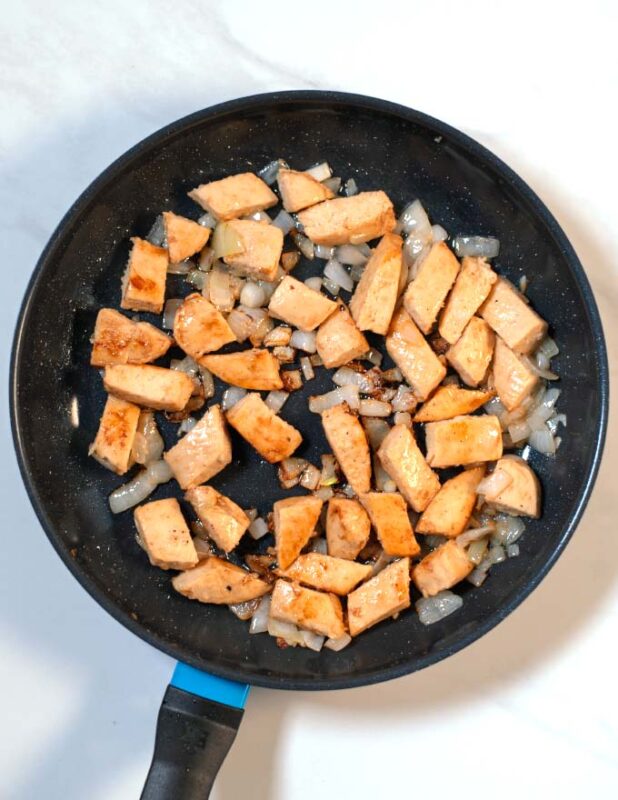 Vegan chicken is fried with onions in a pan.