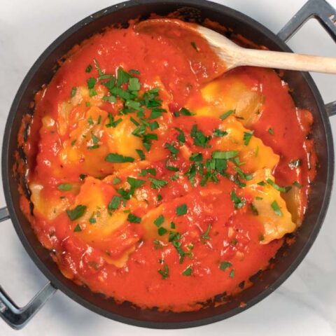 A large serving of ravioli in sauce, garnished with fresh parsley.