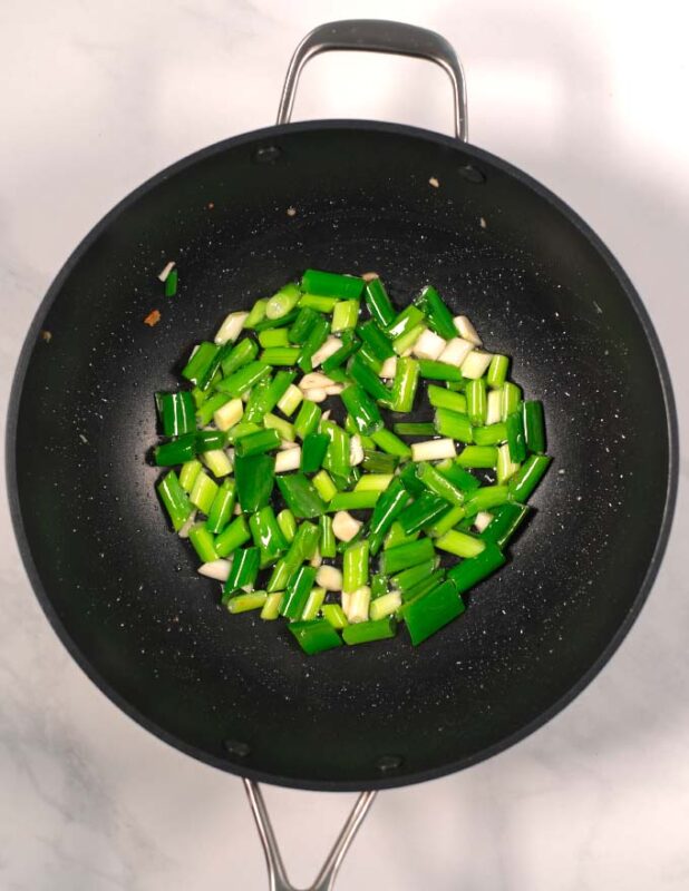 Scallions are added to the large pan.