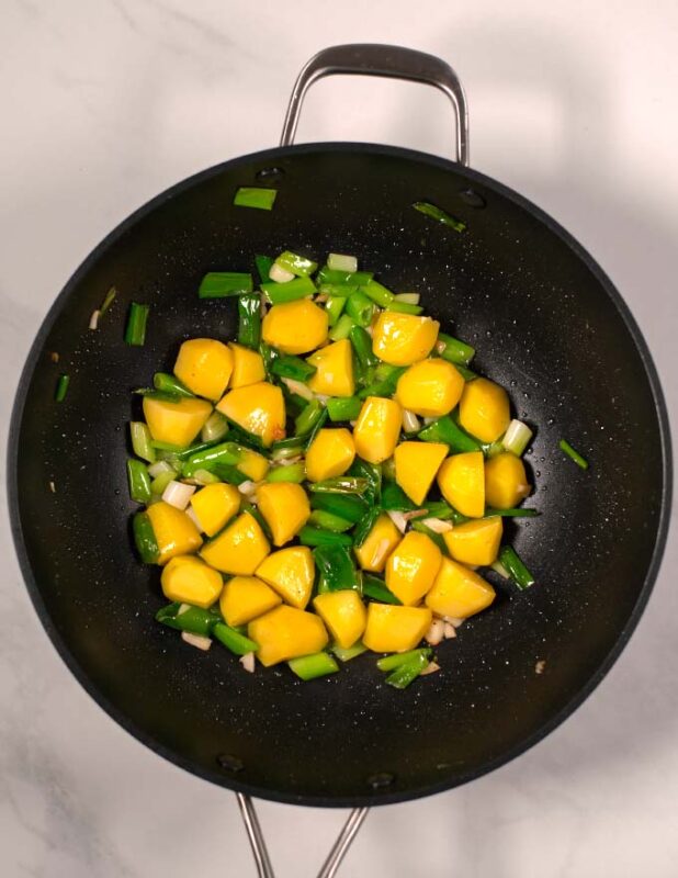 Peeled potatoes are mixed with the scallions and fried.