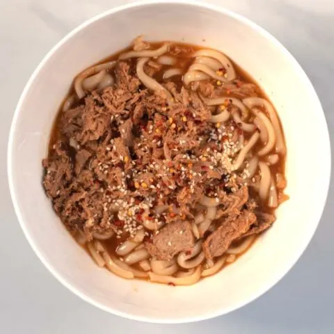 Sesame seeds and chili flakes are used to harnish Beef Udon Noodles.