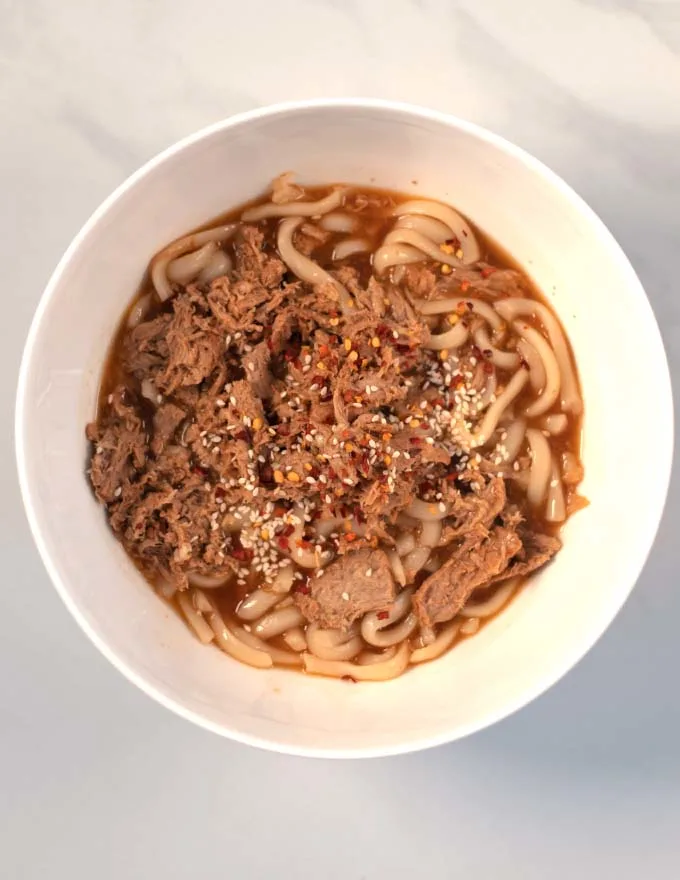 Sesame seeds and chili flakes are used to harnish Beef Udon Noodles.
