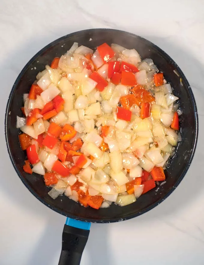 Onions and peppers are fried in a pan.