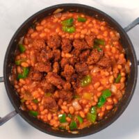 Browned sausage bits are given to the bean chili.