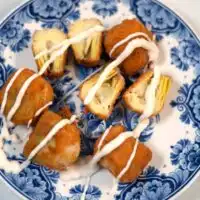 A plate of fried artichoke hearts sprinkled with sauce.
