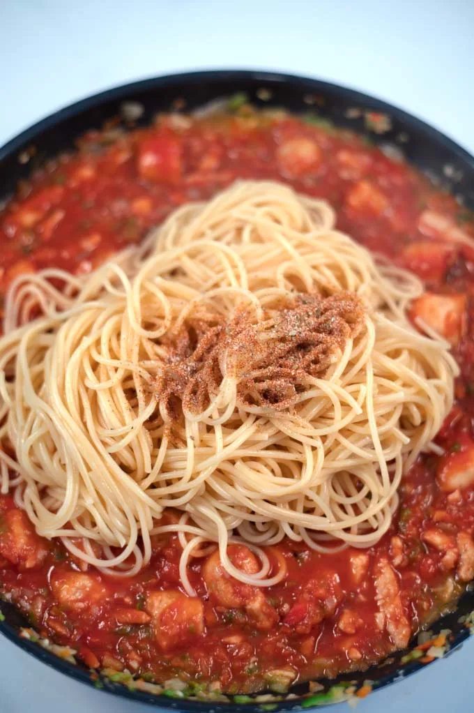 Closeup of seasoned pasta on top of Jambalaya sauce.