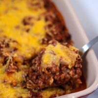 A spoonful of Lentil Casserole is lifted from the baking dish.