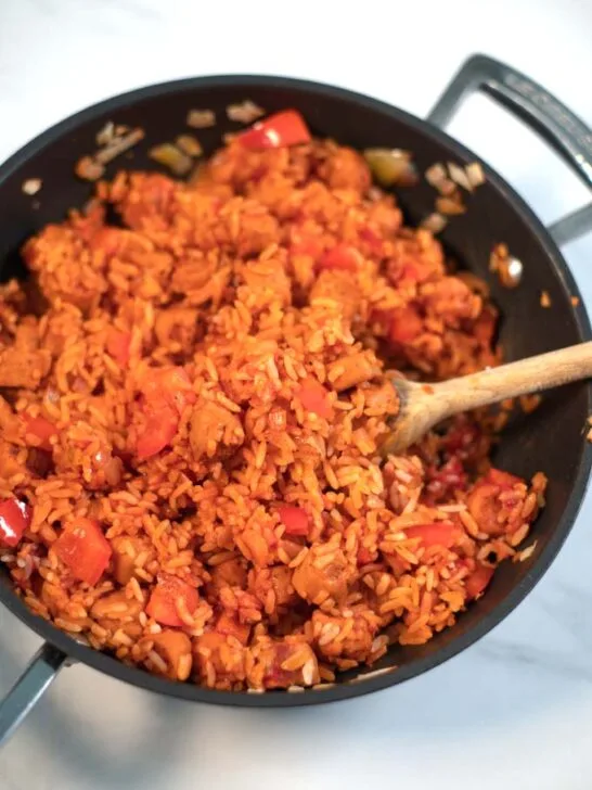 A wooden spoon in Smoked Sausage and Rice.