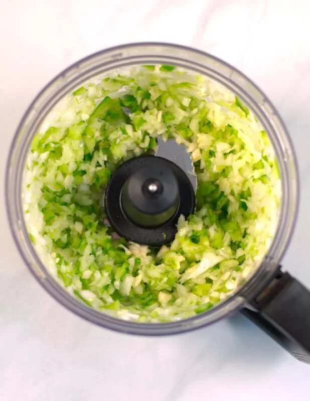 Onions, garlic, and bell pepper in a food processor after chopping.