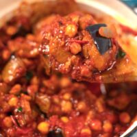 A wooden spoon lifts Lebanese Moussaka from the pot.