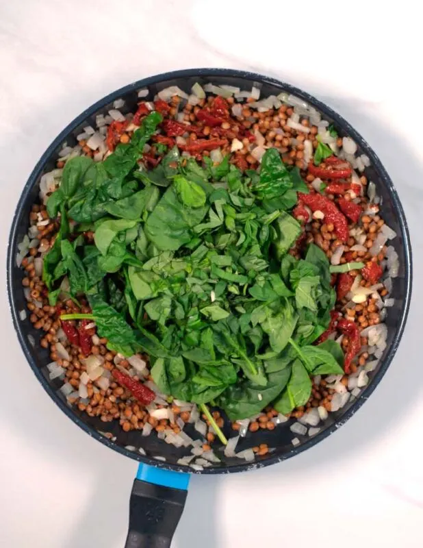 Basil and baby spinach are given to the pan.