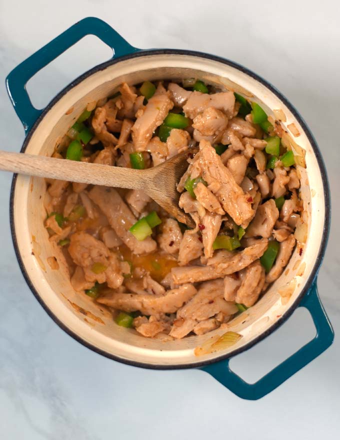 Vegan chicken, green bell pepper and spices are cooked in a saucepan.