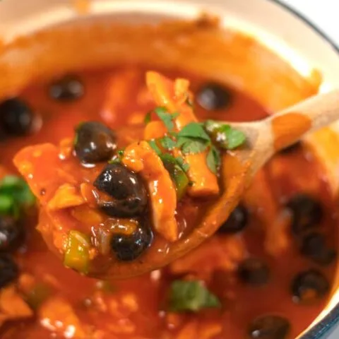 Closeup to a wooden spoon with Spanish Chicken Stew.