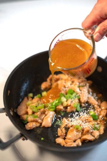 Chinese Orange Sauce is poured over chicken in a pan.