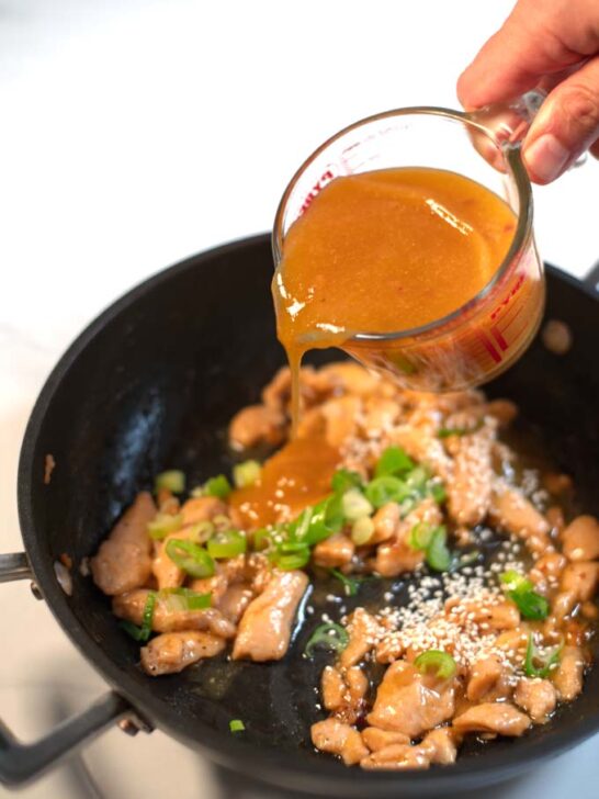 Chinese Orange Sauce is poured over chicken in a pan.