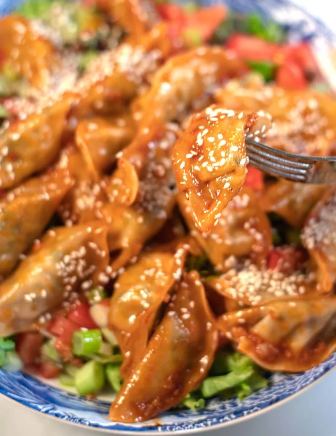 A fork lifts one dumpling from the Dumpling Salad.