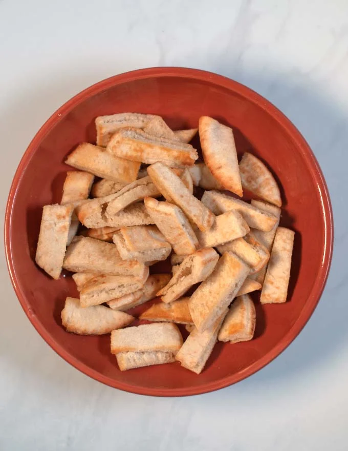 Toasted pita bread slices are given as base into a large plate.