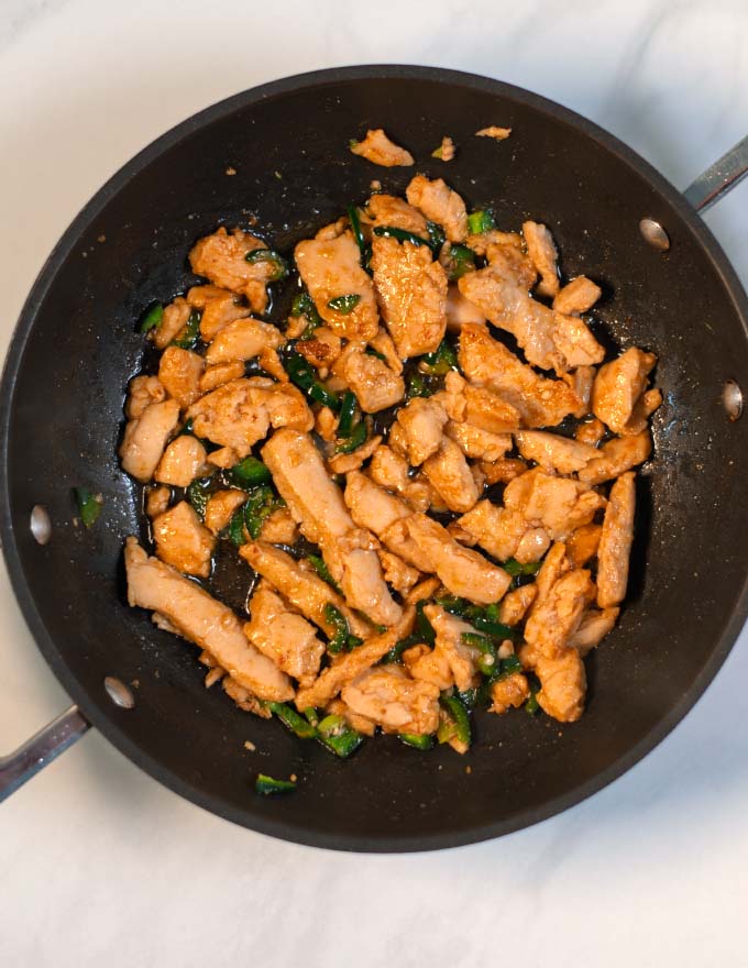 Chicken sauteed with jalapenos in a pan.