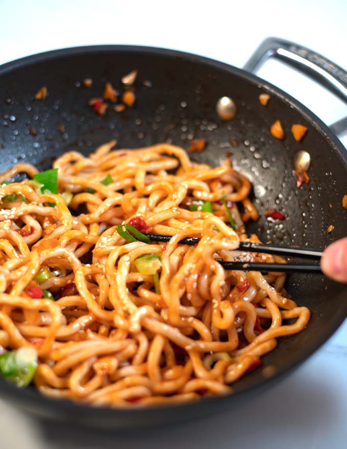 Some noodles with Thai Seasoning Sauce are lifted from the pan with chop sticks.