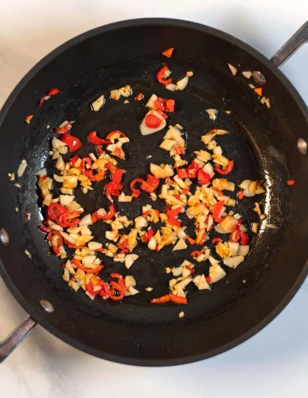 Chopped spices are fried in a pan.