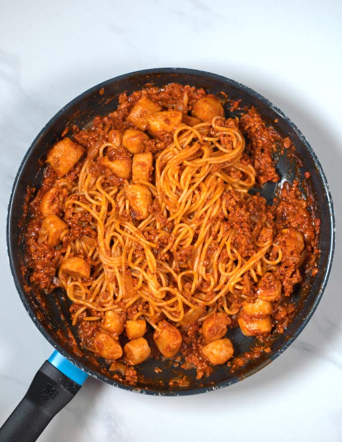 Spaghetti are added to pan.