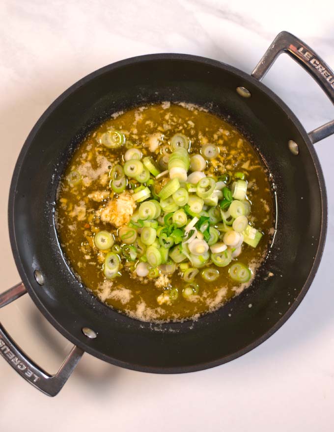 Scallions are given to the pan with buttered garlic and ginger.