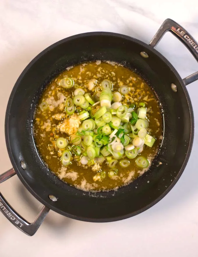 Scallions are given to the pan with buttered garlic and ginger.