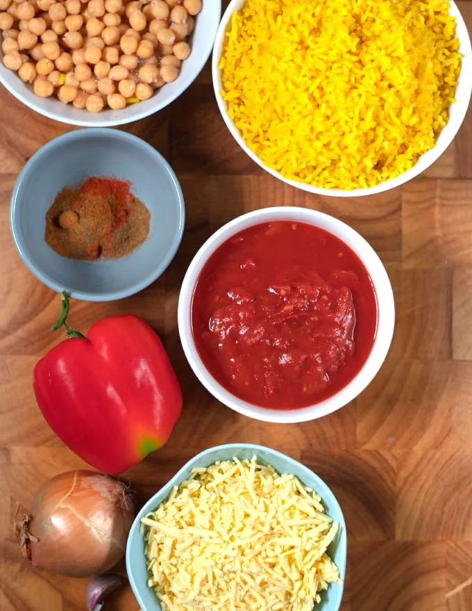 Ingredients needed to make Leftover Spanish Rice Bake collected on a wooden cutting board.