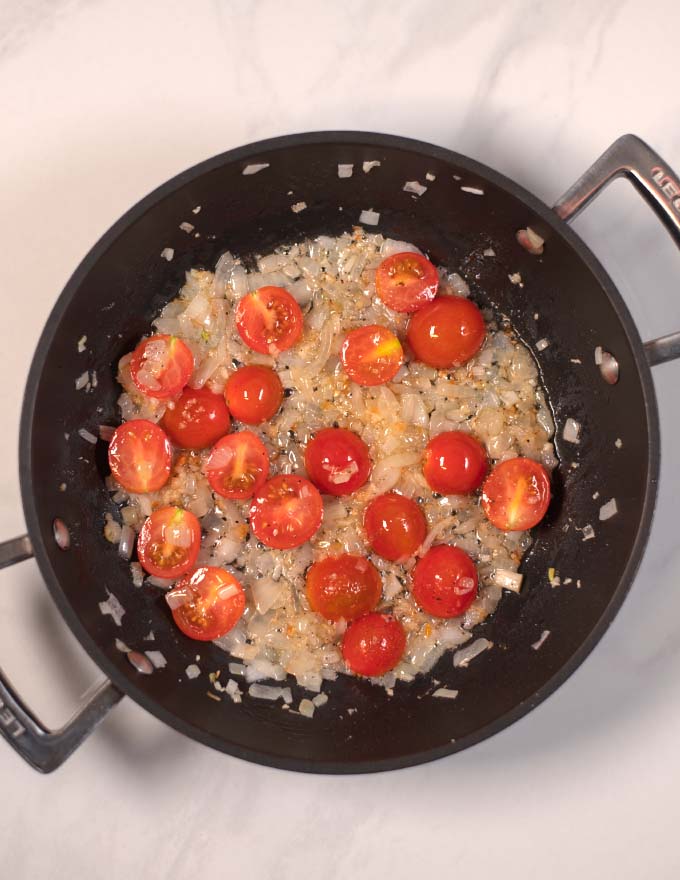 Halved cherry tomatoes are added to the onions.