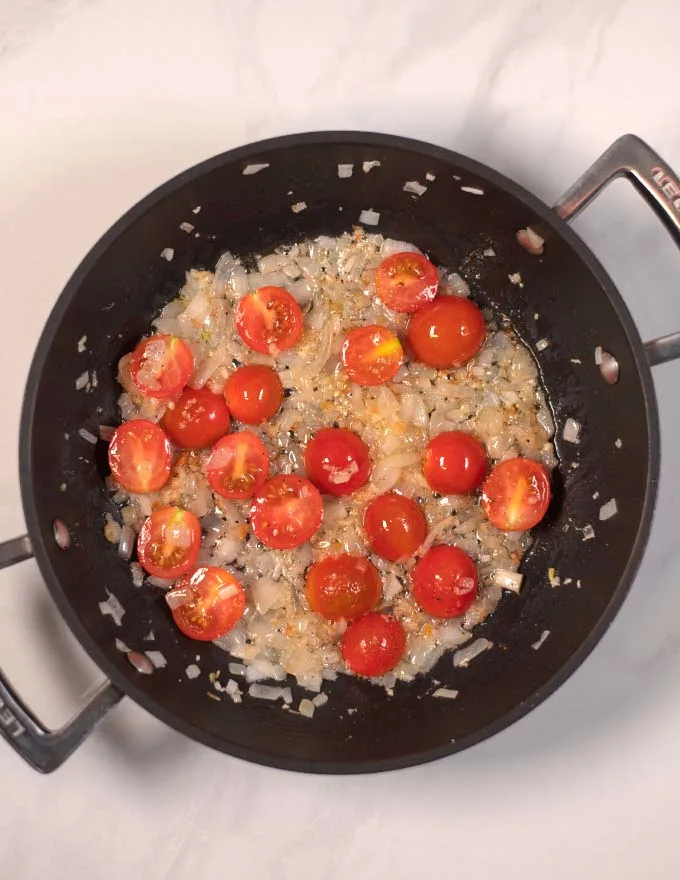 Halved cherry tomatoes are added to the onions.