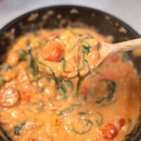 A large spoon lifts Marry Me Butter Beans from a pan.
