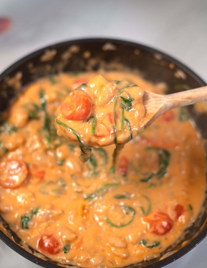 A large spoon lifts Marry Me Butter Beans from a pan.
