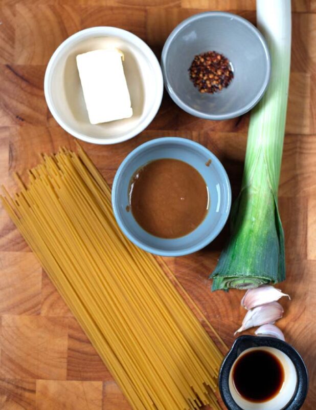 Ingredients needed to make Miso Pasta are collected on a wooden board.