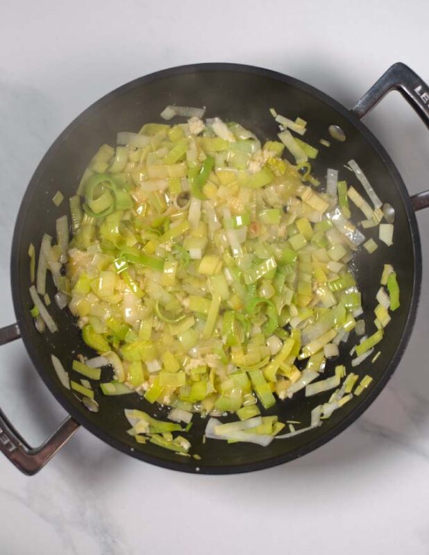 A frying pan with butter and leek.