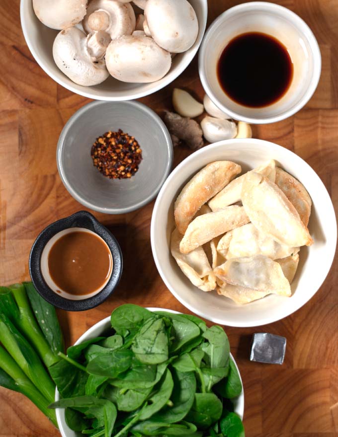 Ingredients needed for making Potsticker Soup collected on a wooden board.