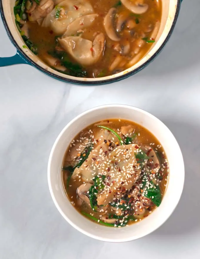 A serving of Potsicker Soup in a white serving bowl with the pot in the background.