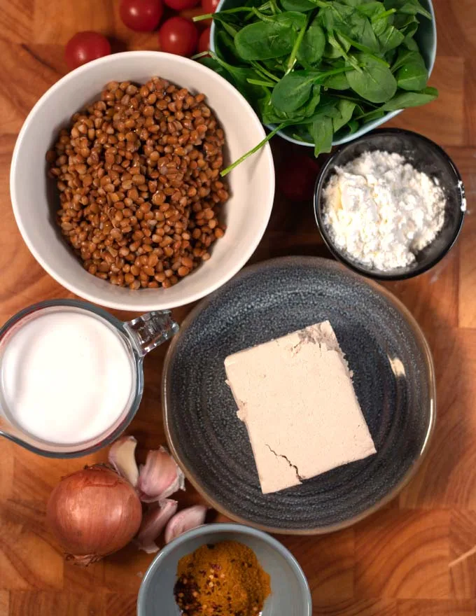 Ingredients needed to make Tofu Curry on a wooden cutting board.