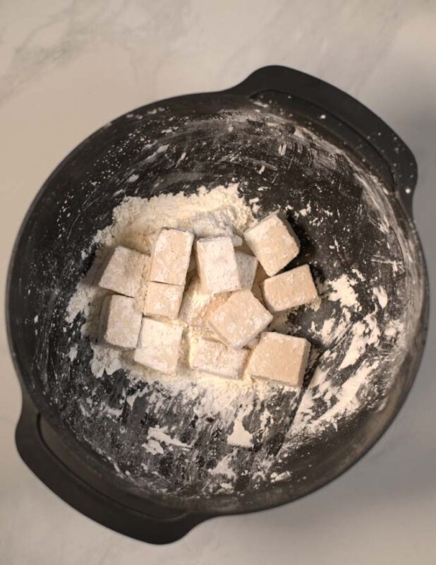 Cornstrach coated tofu cubes in a mixing bowl.