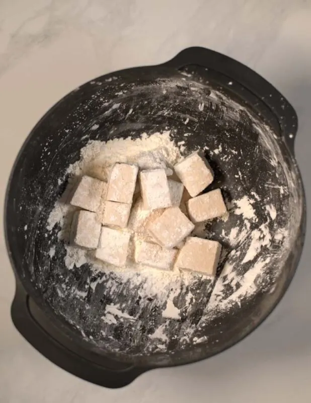 Cornstrach coated tofu cubes in a mixing bowl.